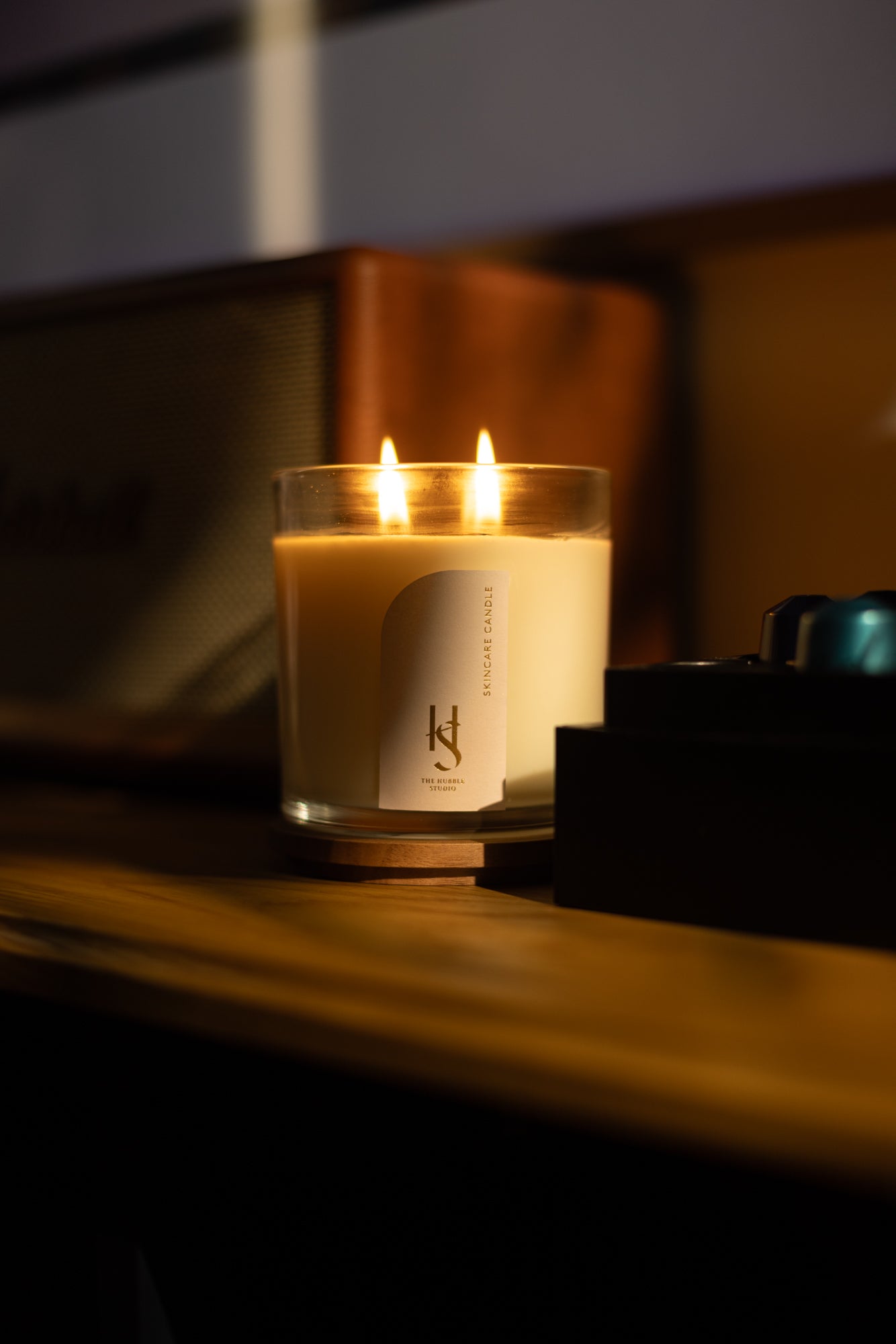 The Hubble Studio Skincare Candle lighting up on table